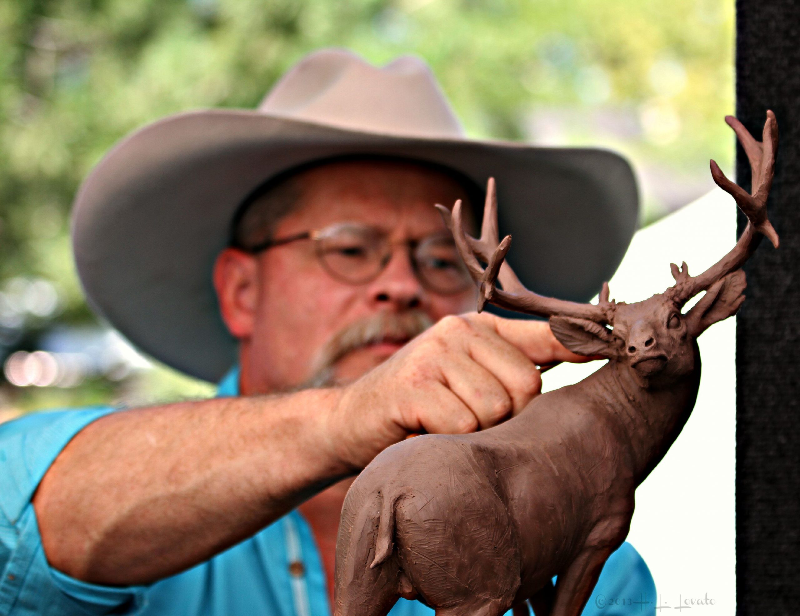 Man sculpting an elk out of clay