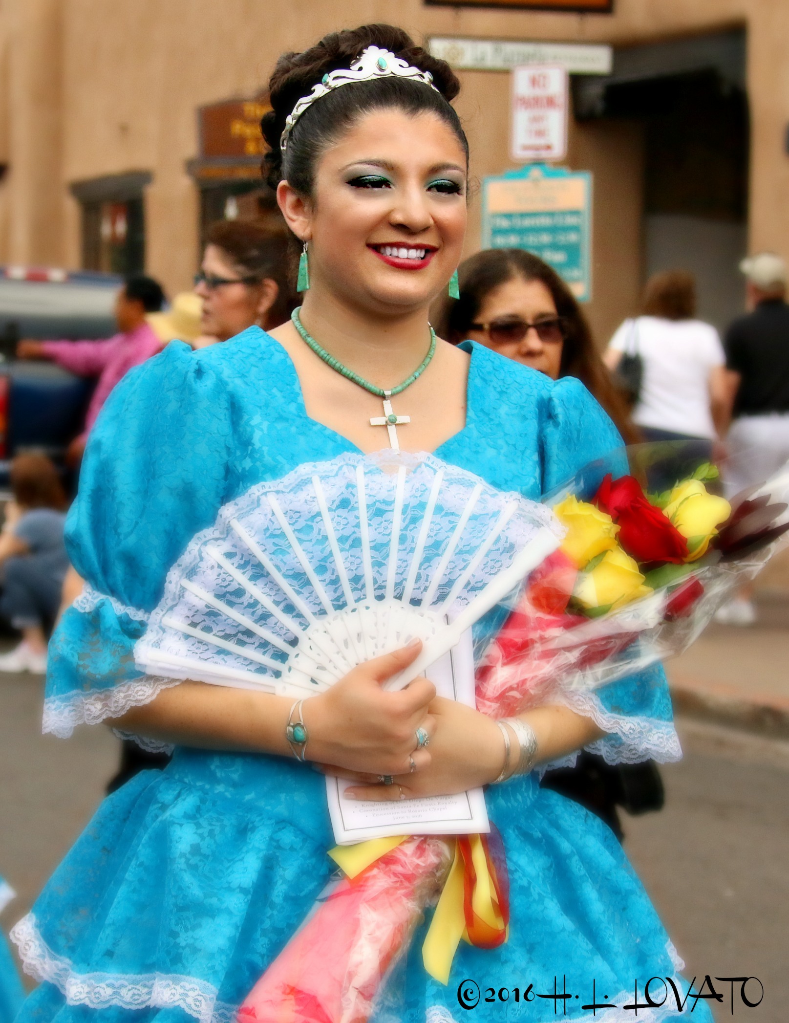 Woman dressed in a bright blue gown holding a lace fan